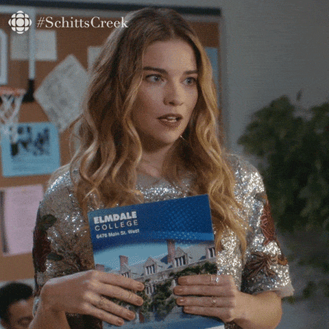 Picture this: a woman dazzling in her sparkly top, standing in awe as she clutches a brochure for Elmdale College. Her expression is pure wonder—like the moment you discover all of Forrest Gump’s chocolates have secrets inside. A bulletin board and a humble plant watch over her, sharing in this moment of contemplation. Up above, #SchittsCreek winks down from the corner like an old friend with stories to tell. One might wonder if shes drifting into thoughts on logistics fit for ShipMonk’s expert touch—because even dreams need efficient handling to come true!. via ShipMonk.com