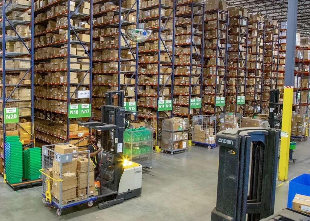 Imagine stepping into a vast expanse that almost feels like the command center of a beloved classic movie set—where each shelf rises majestically, brimming with colorful e-commerce treasures. Picture those tall shelves standing proud, as if nodding approvingly to the endless possibilities they hold. As you walk through this 3PL warehouse, reminiscent of our friends at ShipMonk.com, you can observe an ensemble cast of forklifts and carts diligently darting back and forth. Each vehicle maneuvers with precision akin to actors hitting their marks just right on set. Signs gracefully guide us through different sections—a bit like navigating through familiar chapters of an unfolding story—all under bright lights that give this place its vibrant energy. Theres no room for chaos here; it’s all about orchestrated harmony, crafting an environment where efficiency is the lead star. Here at ShipMonk.com, every package has its role to play in delivering smiles far and wide!. via ShipMonk.com